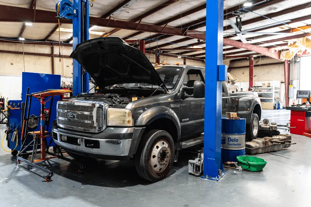 Diesel maintenance, diesel repair in Brooksville, FL by RDI Power. Image of a Ford F-350 on a lift with the hood open and rear wheel removed inside a diesel repair shop, showcasing heavy-duty service and maintenance work.