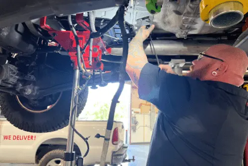 Transmission Fluid Leaks in Diesel Trucks | RDI Power’s Maintenance Tips. Image of mechanic installing new transmission on diesel truck in shop.