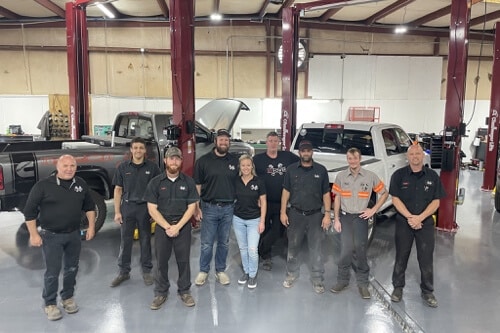 New Year, New fully equipped Diesel Service and Repair Facility in Brooksville, FL with RDI Power; image of RDI team standing in new shop bay with diesel pickup trucks on lifts behind them